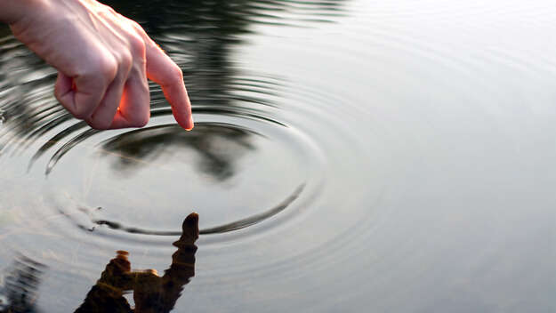 Hand berührt Wasser.