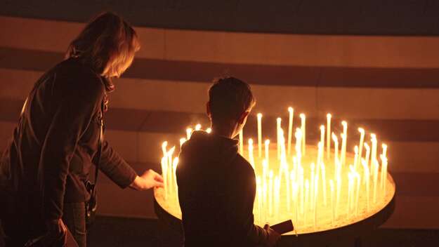Eine Frau und ein Kind entzünden Kerzen im Osternnachtgottesdienst