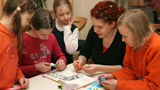 Gemeindepädagogin arbeitet mit Mädchen bei den Kinderbibeltagen der Evangelischen Kirchengemeinde in Lohmen, Sachsen. Malen, zeichnen, basteln, besprechen von Themen wie Weltgebetstag und Kenntnis über das Weltgebetstagsland.