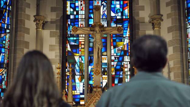 Frau und Mann stehen in der Gartenkirche St. Marien in Hannover vor dem Kreuz