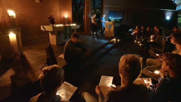 Ein Gruppe von Menschen feiern einen Gottesdienst mit vielen Kerzen.