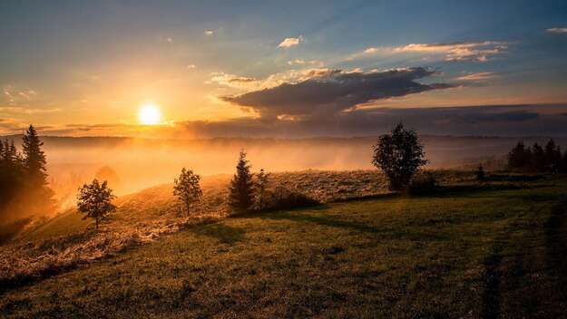 Aufgehende Sonne über einer Hügellandschaft