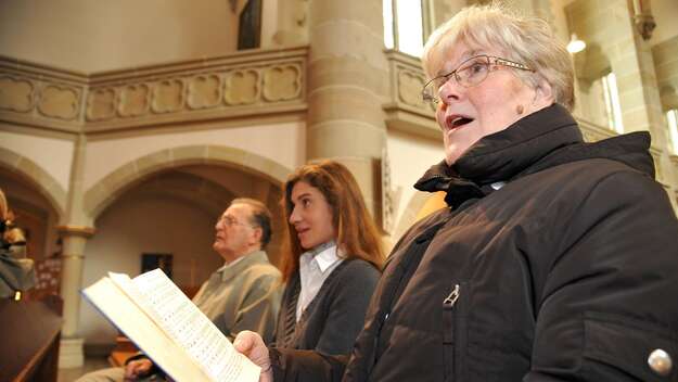 Singende Gottesdienstbesucherin, ein Gesangbuch in der Hand haltend