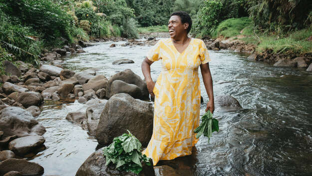 Luisa Curuki (35) waescht Bele-Blaetter im Fluss hinter ihrem Hausin Fiji, Fidschi