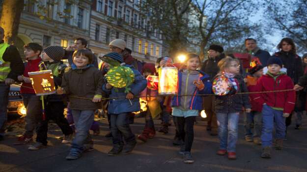 Kinder laufen mit bunten Laternen durch die Straße Kinder laufen mit bunten Laternen durch die Straße