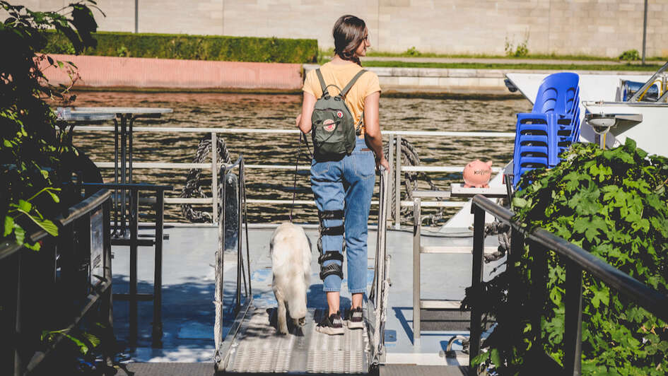 Eine junge Frau mit einer Schiene am Bein benutzt einen Aufzug am Bahnhof.