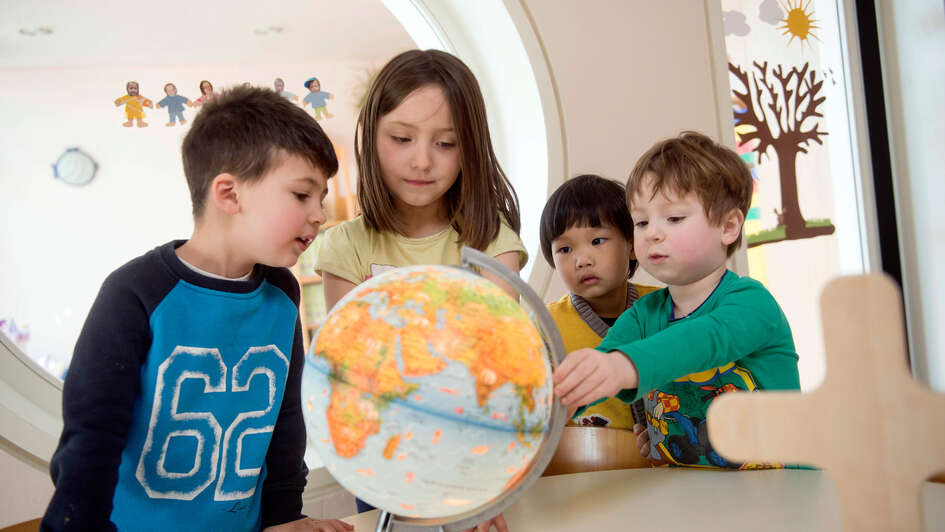 Kinder spielen mit einem Globus im evangelischen Kindergarten 'Brummkreisel' im westfälischen Espelkamp.