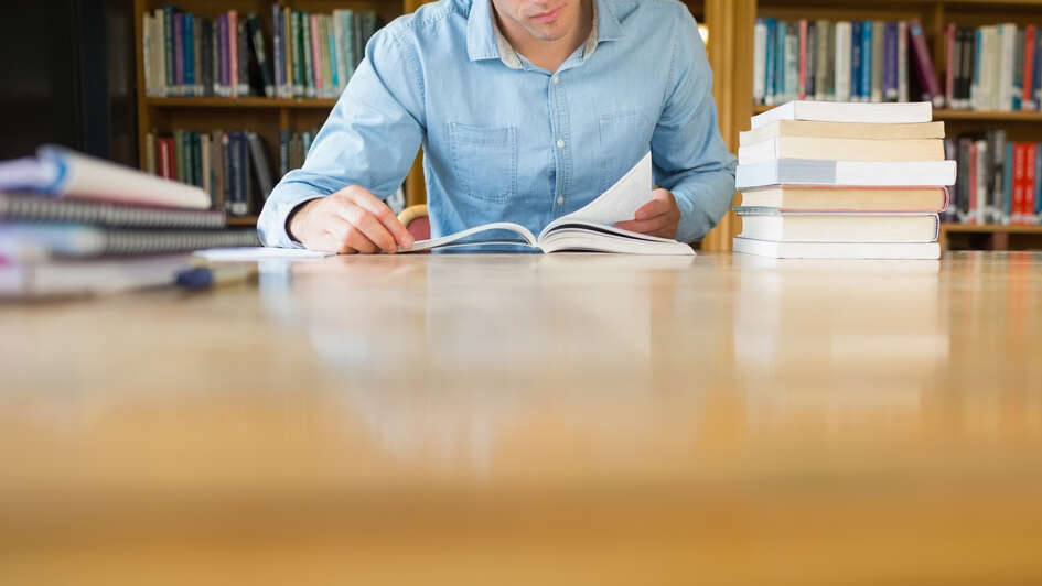 Ein Mann liest in  einer Bibliothek