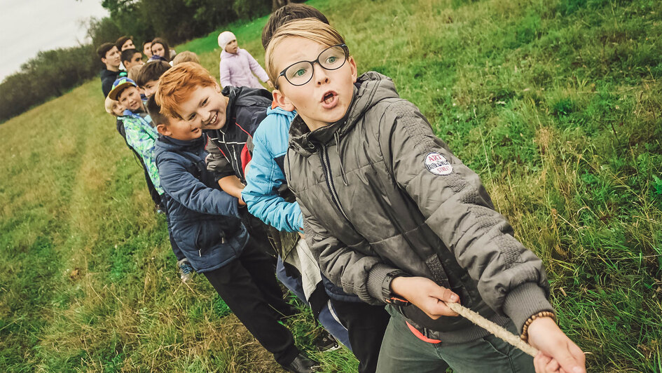 Kinder und Erwachsene ziehen an einem Seil