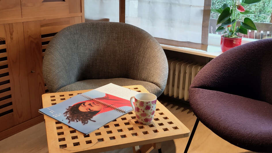 Auf einem kleinen Tisch liegt der Fastenkalender neben einer Kaffeetasse