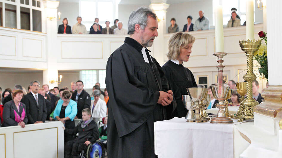 Pfarrerin und Pfarrer zelebrieren am Altar