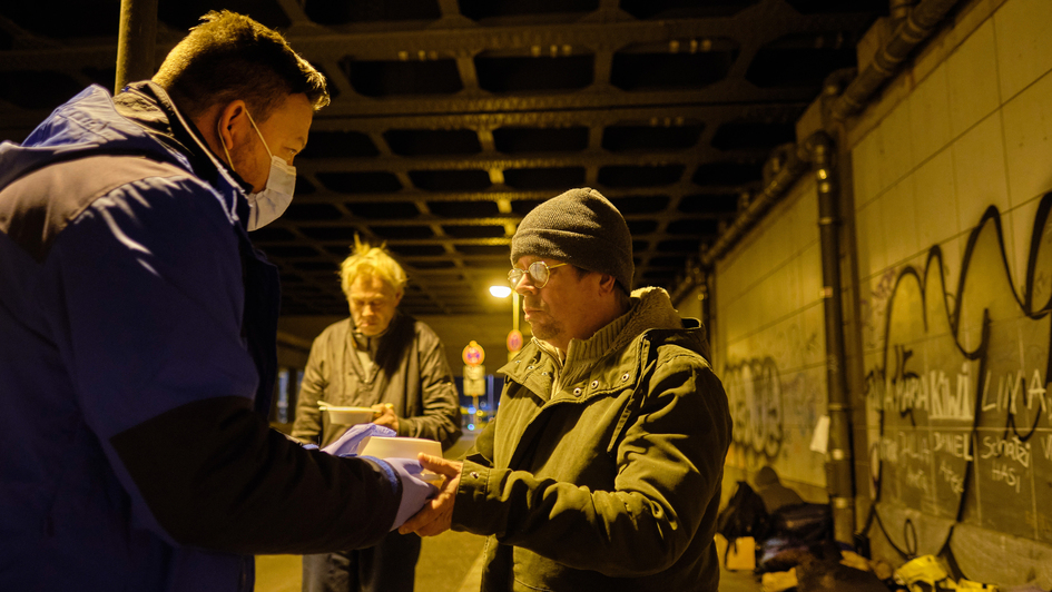 Daniel (li.), Trainer beim FC Staacken in Berlin, ist am Abend des 20.11.2020 mit dem Suppenbus der Berliner Stadtmission unterwegs um Obdachlose mit Essen und heissem Kaffee zu versorgen. (Foto unter der Bruecke Ostbahnhof) Daniel hat Chili con Carn​e ge