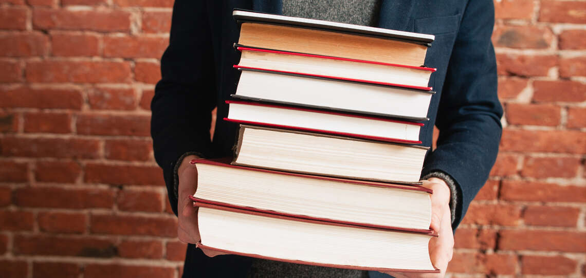 Mann mit einem Stapel Bücher in der Hand.