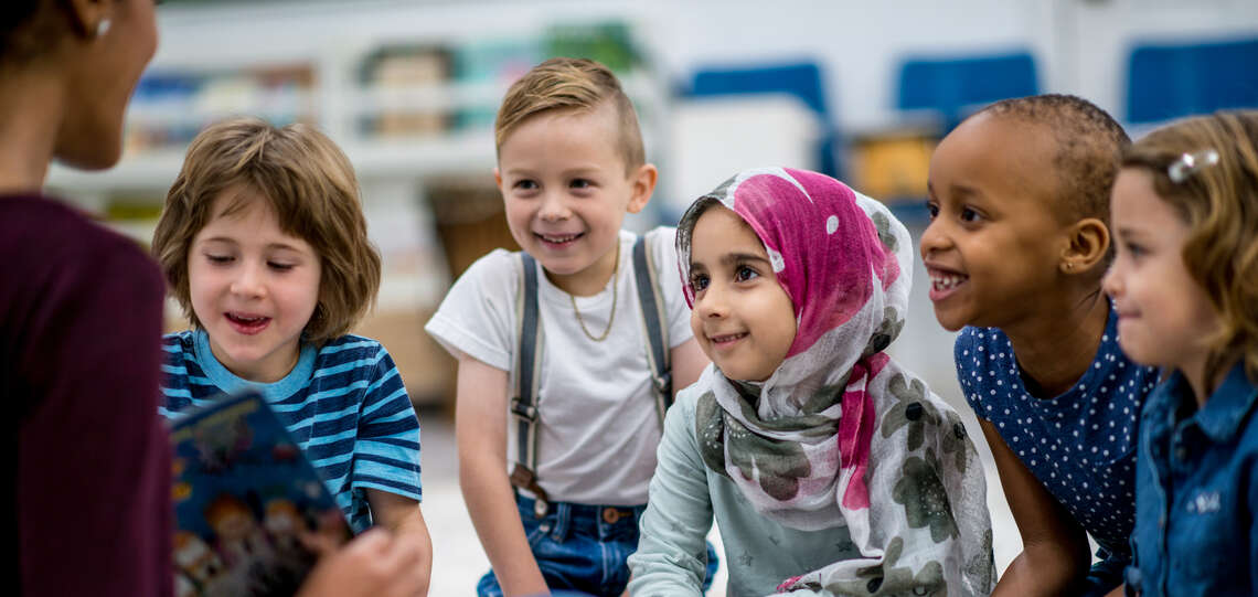 Lehrerin mit multikultureller Gruppe von Kindern.