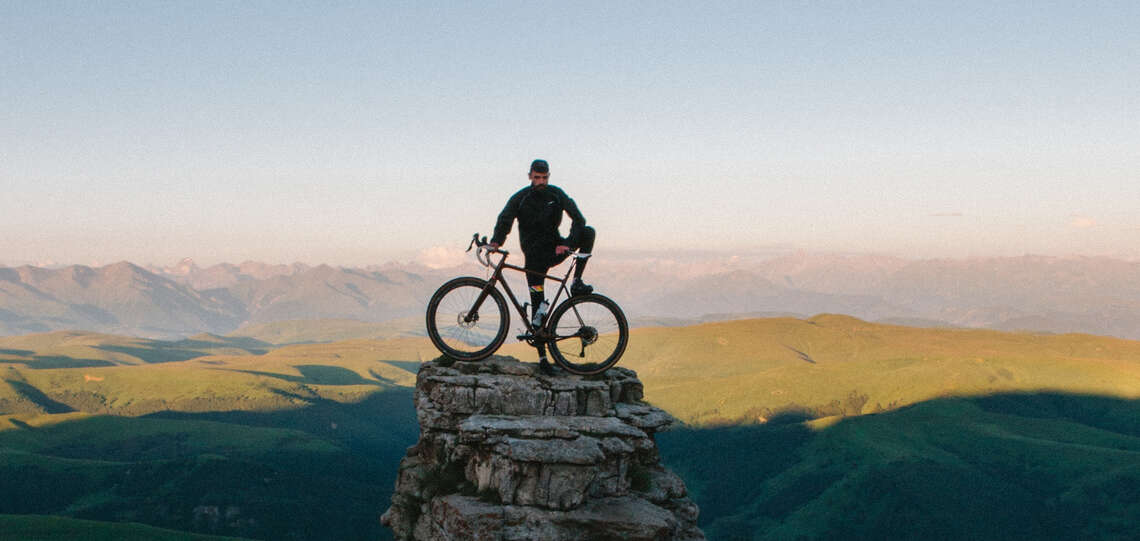 Mann steht mit einem Fahrrad auf einem Berg