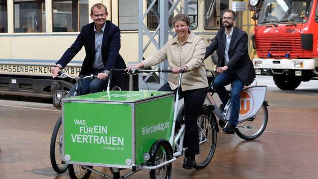 Stefanie Rentsch (mitte), Studienleiterin des Kirchentages, Axel Rolfsmeier (li.), Projektleiter der Kooperation Nachhaltigkeit, und Christof Hertel (re.) von der Stabsstelle Umwelt des Kirchentages stellen die Lastenräder vor, die auf dem Kirchentag in D