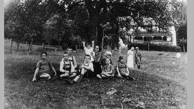DietrichBonhoeffer im Jahr 1911 mit seinen sieben Geschwistern, der Erzieherin Maria Horn und den Eltern im Sommer 1911 vor dem Ferienhaus im schlesichen Wölfelsgrund.