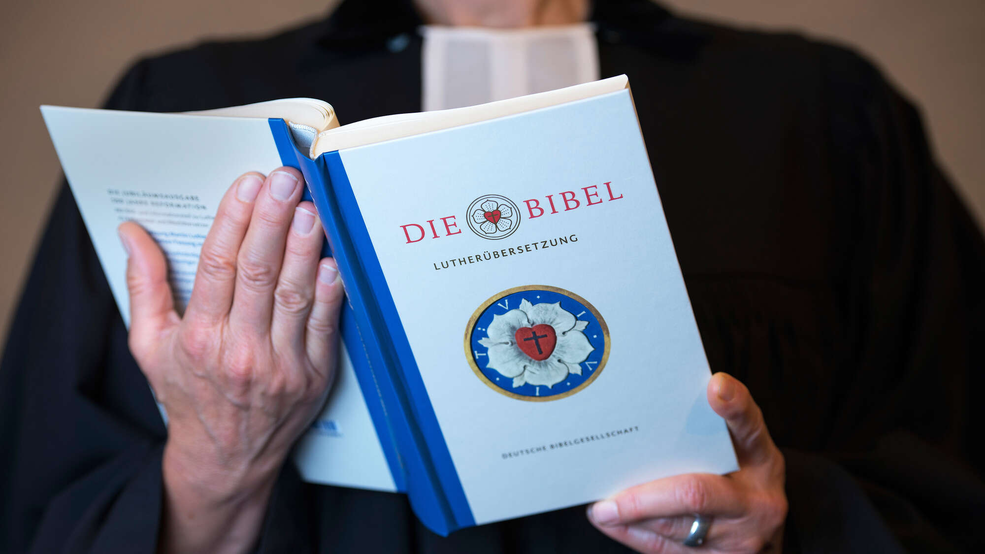 Pfarrerin im Talar mit einer Lutherbibel in der Hand