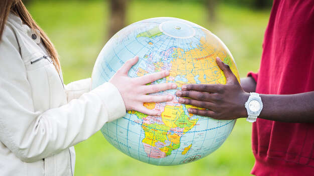 Man and woman holding a globe between themselves.