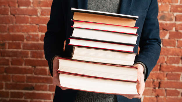 A man with a stack of books in hands.